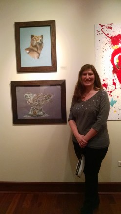 Northern grey wolf in pastel (top), Snowy owl in colored pencil (bottom).  Me standing with two of my pieces in the show.